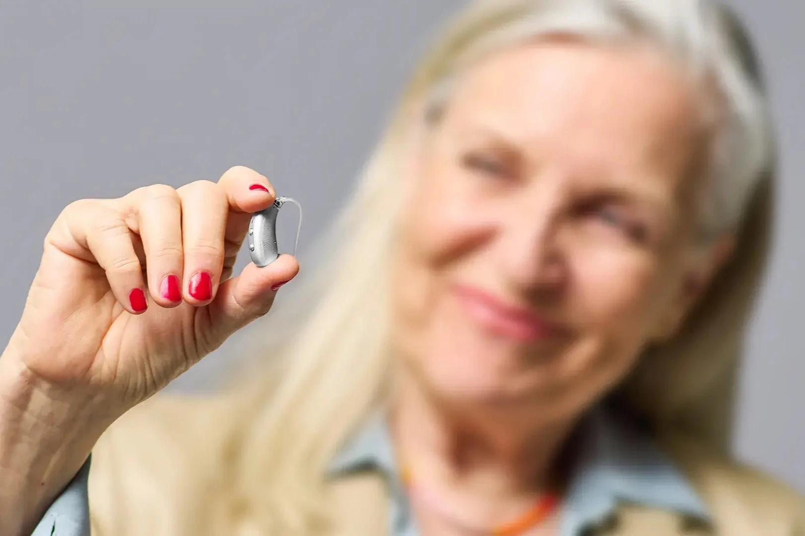 Elderly woman holding a Signia hearing aid